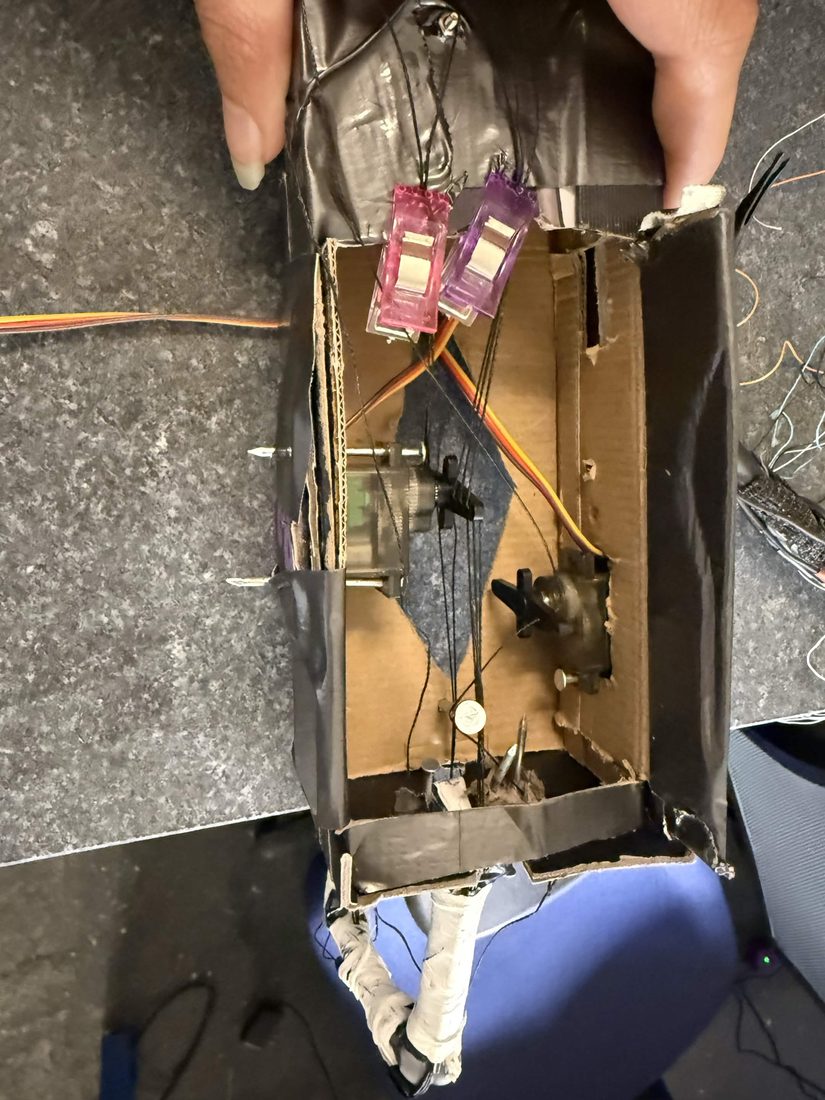 servos mounted in a cardboard box pulling tendon threads